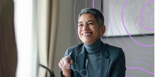 Grey haired professional woman holding glasses smiling